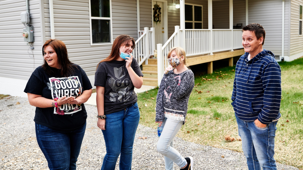 A family stands in front of their first owned home in Ary, Kentucky